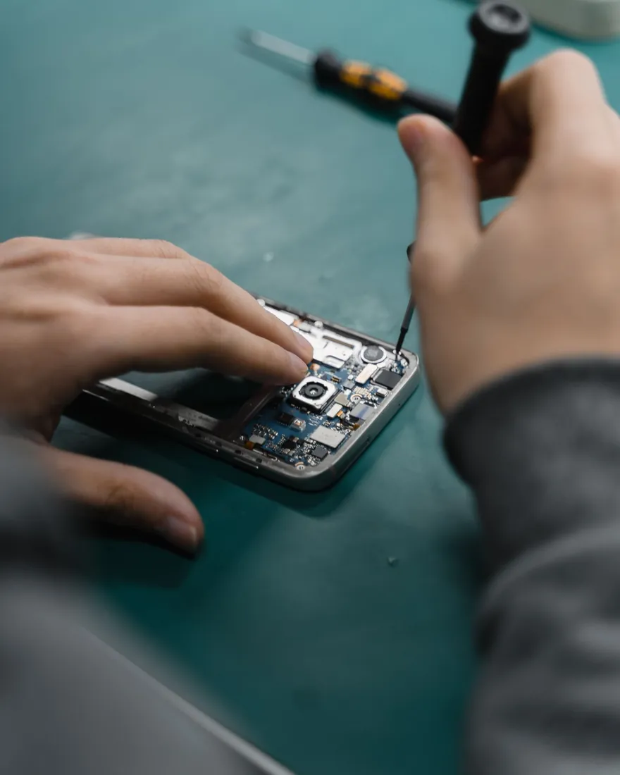Manos desmontando un móvil con un destornillador de precisión
